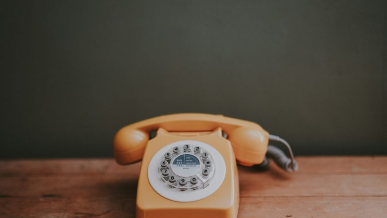 brown rotary-dial telephone in a grey room