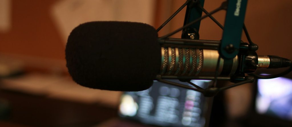 a studio microphone on its arm in a soundproofed booth